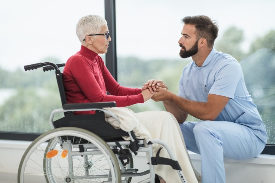A caregiver kneeling to talk with a resident at eye level